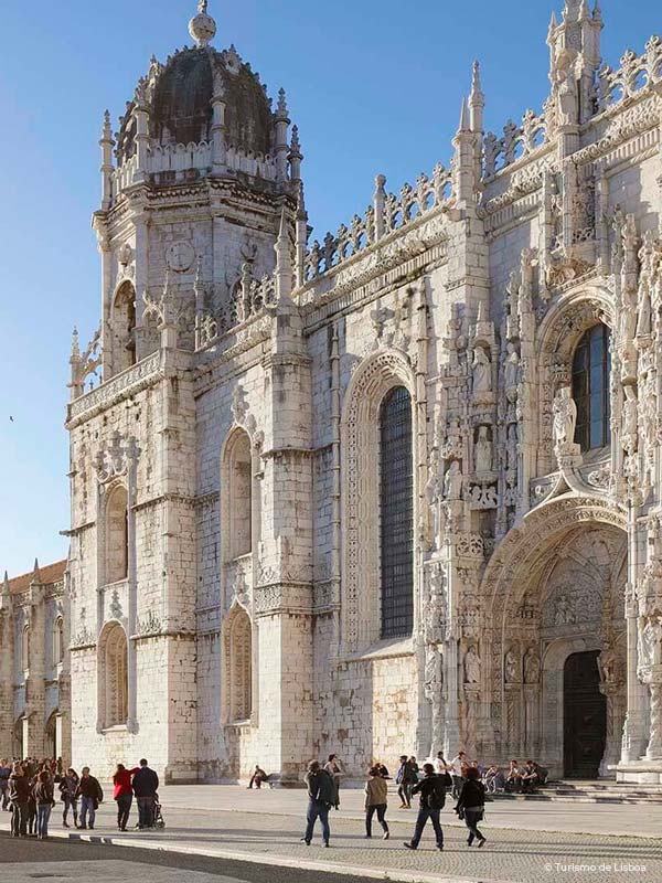 Outside of the monastery of Jeronimos in Belem, Portugal in a sunny day, with people outside.