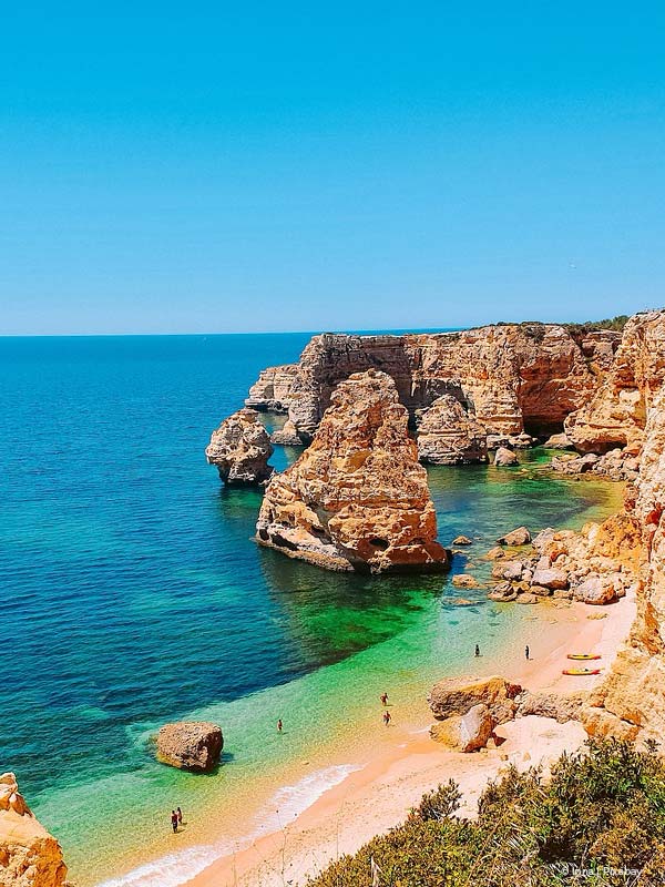 Beach of Benagil in Lagoa, Algarve region in Portugal, with gold sand, blue and green ocean and rocks, on a sunny day with blue sky.