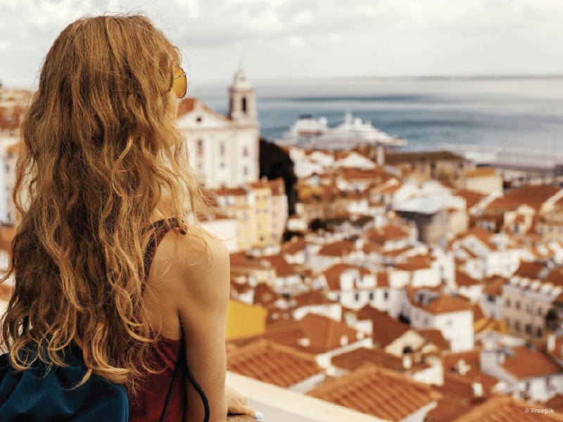 Woman overlooking the city of Lisbon from above in a cloudy day.