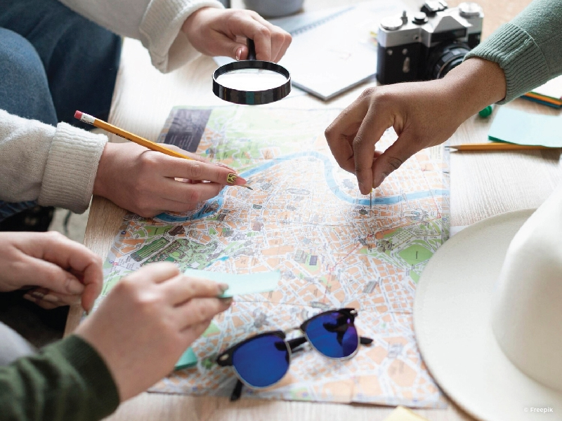 Close view of a map and hands pointing and at locations.