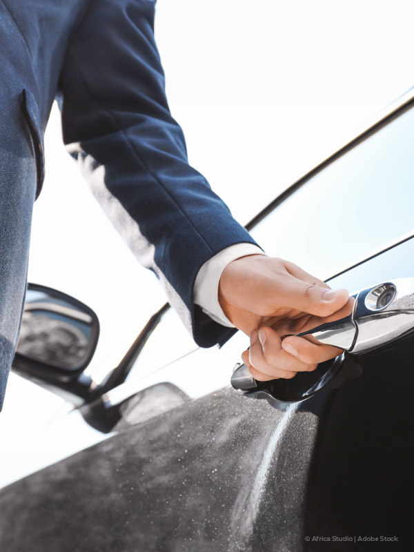 Close-up view of a man opening a car door.