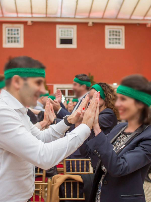 Smiling man and woman wearing green bandanas on their foreheads while joining hands during a team building activity.