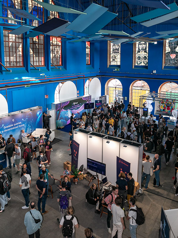 Group of people gathering at a conference inside a warehouse decorated in tones of blue.